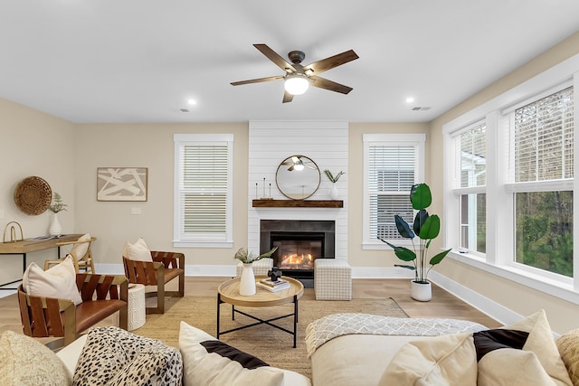 living room with visible vents, baseboards, light wood-style flooring, and a ceiling fan