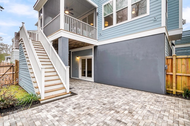 view of patio / terrace with stairway, a sunroom, and fence