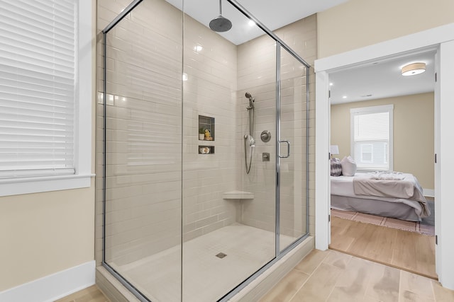 bathroom with ensuite bath, baseboards, a stall shower, and wood finish floors