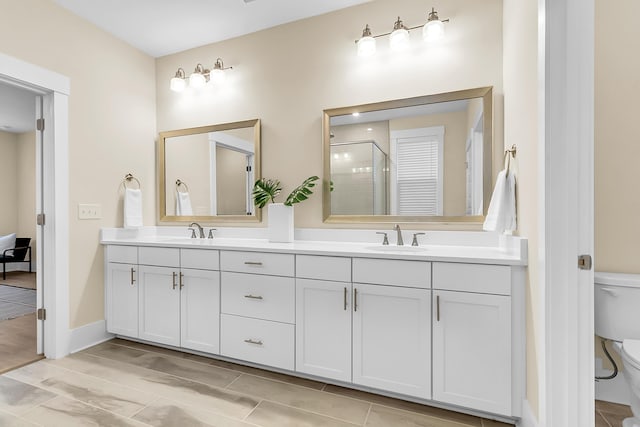 bathroom with double vanity, a shower stall, toilet, and a sink