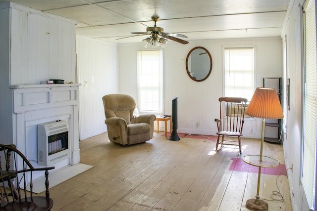 sitting room with a fireplace, a ceiling fan, heating unit, and light wood-style flooring