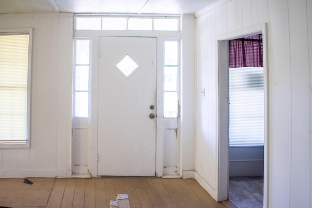 foyer featuring light wood-style flooring and wood walls