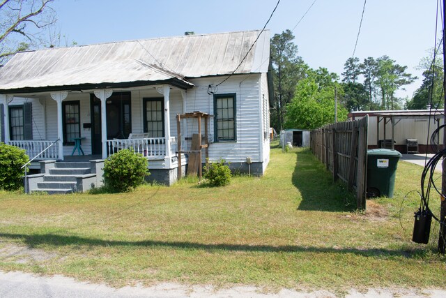 bungalow with a front lawn, metal roof, and covered porch