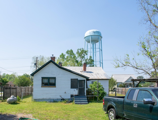 rear view of property featuring a lawn, fence, and a chimney