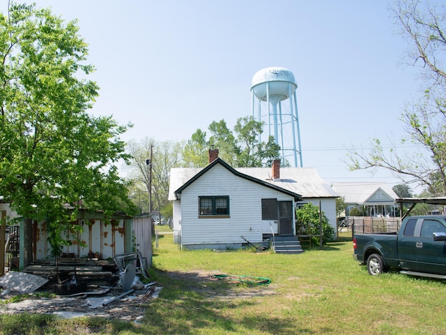 back of property with a lawn and a chimney