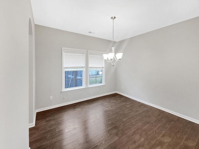 empty room with visible vents, dark wood-style floors, arched walkways, baseboards, and a chandelier