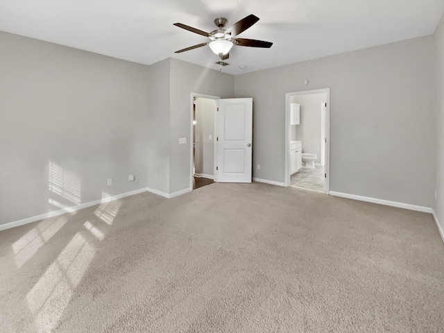 unfurnished bedroom with ceiling fan, light colored carpet, baseboards, and connected bathroom