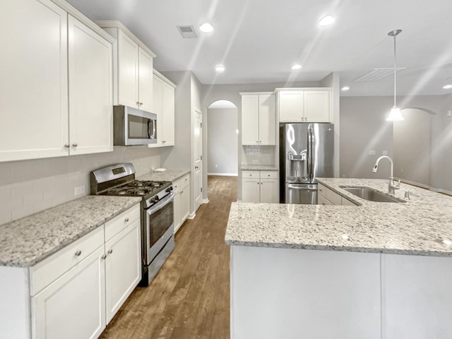 kitchen with visible vents, a sink, wood finished floors, stainless steel appliances, and arched walkways