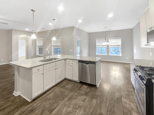 kitchen with recessed lighting, appliances with stainless steel finishes, arched walkways, dark wood-style floors, and a sink