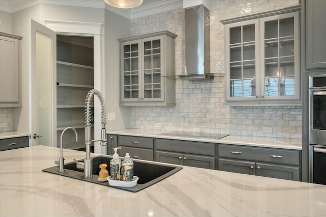 kitchen with gray cabinetry, light stone counters, black electric cooktop, and wall chimney exhaust hood