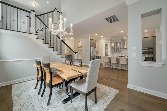 dining room featuring an inviting chandelier, sink, dark wood-type flooring, and ornamental molding