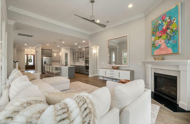 living room with dark wood-type flooring, ceiling fan, ornamental molding, and sink