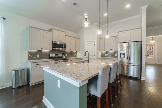 1250 Hammrick Ln, Johns Island, SC 29455 - kitchen with appliances with stainless steel finishes, dark wood finished floors, a kitchen island with sink, decorative backsplash, and light stone counters