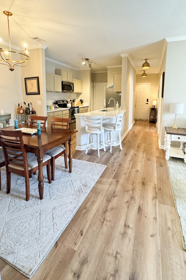 dining room with ornamental molding, a textured ceiling, and light wood finished floors