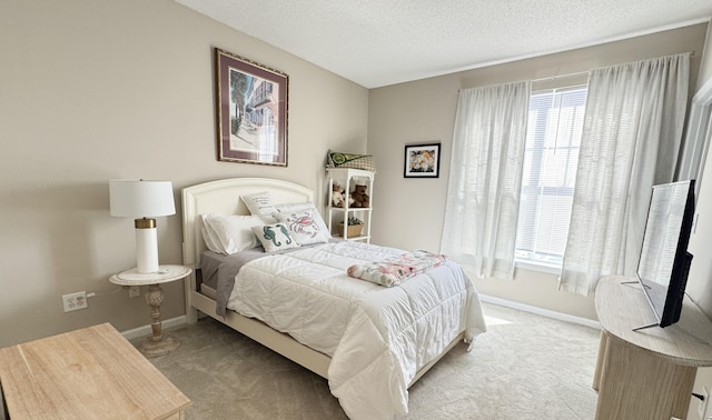 bedroom featuring light colored carpet, a textured ceiling, and baseboards