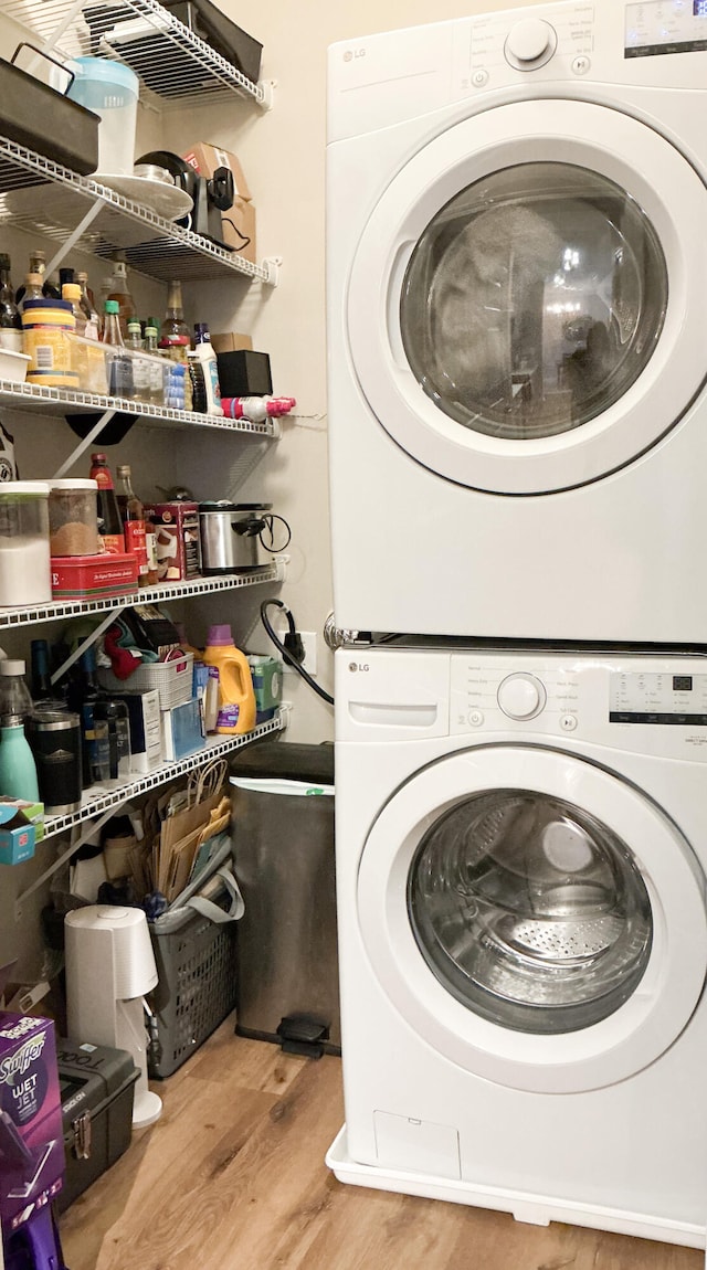 laundry area featuring stacked washer and dryer, laundry area, and wood finished floors