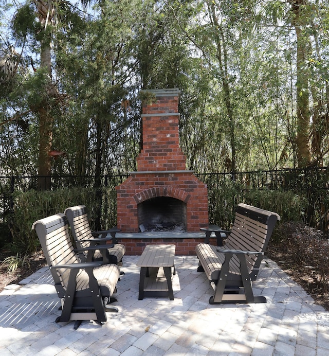 view of patio / terrace featuring an outdoor brick fireplace and fence