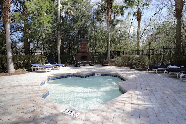 view of pool featuring a patio area, fence, and exterior fireplace