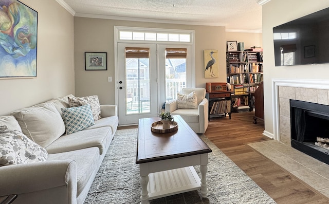 living area with crown molding, a fireplace, a textured ceiling, and wood finished floors