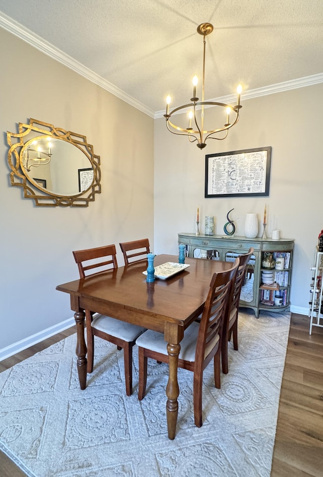 dining room featuring a textured ceiling, ornamental molding, wood finished floors, and baseboards