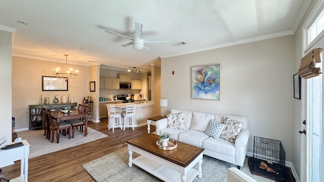 living area with ornamental molding, a textured ceiling, and wood finished floors