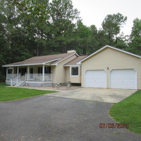 single story home with a front lawn, a garage, and a porch