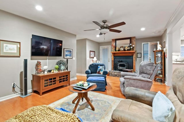 living room featuring hardwood / wood-style flooring, a wood stove, and ceiling fan