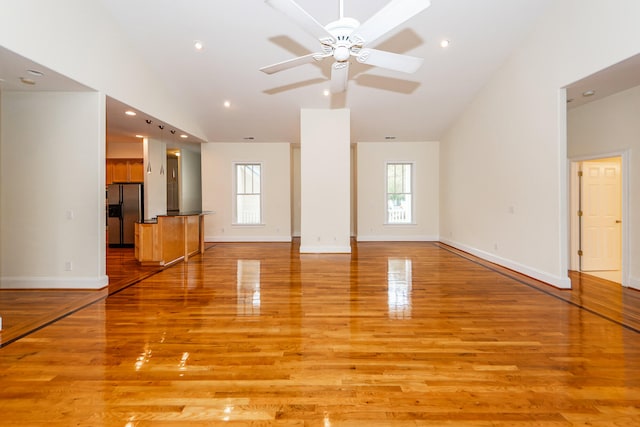 unfurnished living room with ceiling fan, light hardwood / wood-style flooring, and high vaulted ceiling