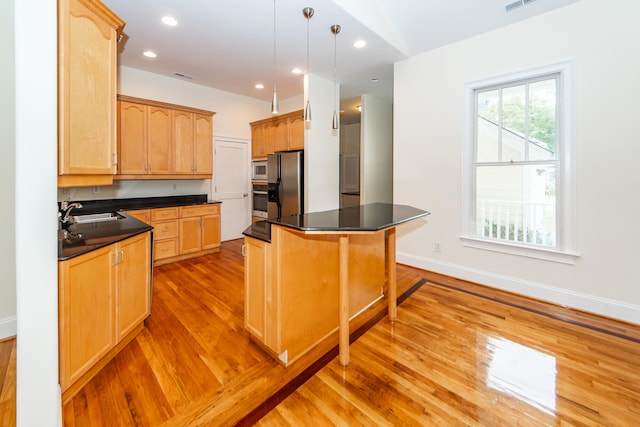 kitchen with a center island, stainless steel appliances, sink, light hardwood / wood-style floors, and decorative light fixtures