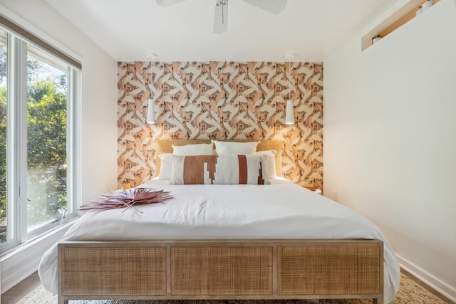 1815 Long Bend Dr, Seabrook Island, SC 29455 - bedroom featuring wallpapered walls, baseboards, an accent wall, a ceiling fan, and wood finished floors