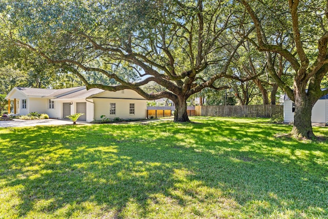 view of yard with concrete driveway, fence, and an attached garage