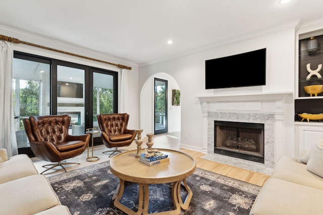 living room with crown molding, a high end fireplace, and light hardwood / wood-style flooring