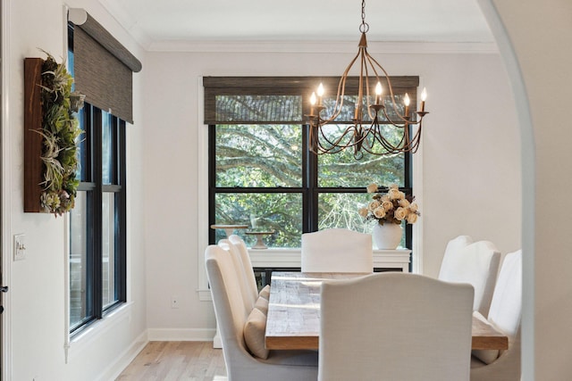 dining area with crown molding, a chandelier, and light wood-type flooring