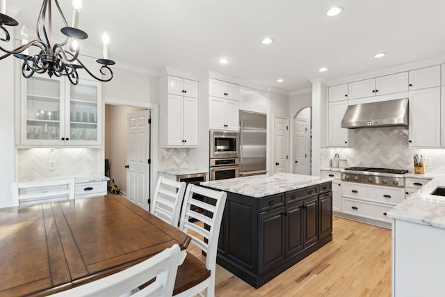 kitchen featuring white cabinetry, crown molding, built in appliances, a center island, and pendant lighting