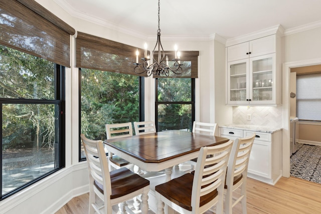 dining space with ornamental molding, a chandelier, and light hardwood / wood-style floors