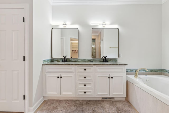 bathroom with crown molding, vanity, and tiled tub