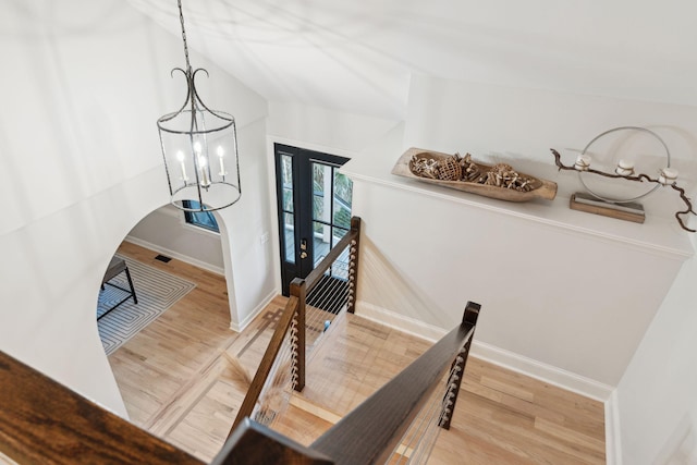 dining room featuring wood-type flooring, vaulted ceiling, and a notable chandelier