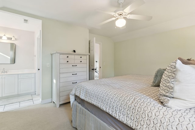 bedroom featuring lofted ceiling, sink, ensuite bath, light carpet, and ceiling fan