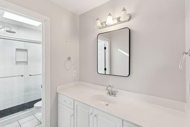 bathroom with vanity, walk in shower, tile patterned floors, and toilet