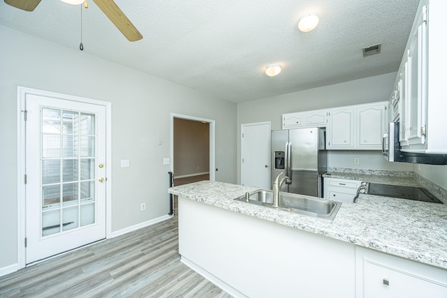 kitchen featuring stainless steel refrigerator with ice dispenser, sink, black range, white cabinets, and light hardwood / wood-style floors