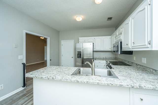 kitchen with sink, light hardwood / wood-style flooring, kitchen peninsula, white cabinets, and appliances with stainless steel finishes