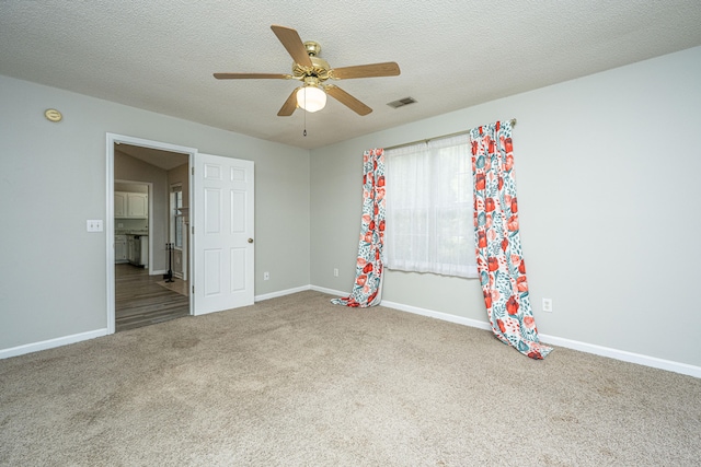 spare room with carpet flooring, ceiling fan, and a textured ceiling