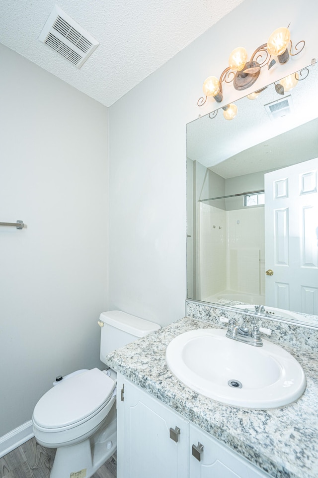 bathroom with vanity, a textured ceiling, a shower, hardwood / wood-style floors, and toilet