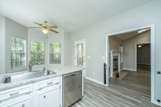 kitchen featuring white cabinets, lofted ceiling with skylight, sink, light hardwood / wood-style flooring, and dishwasher