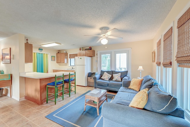 tiled living room with a textured ceiling, ceiling fan, and sink