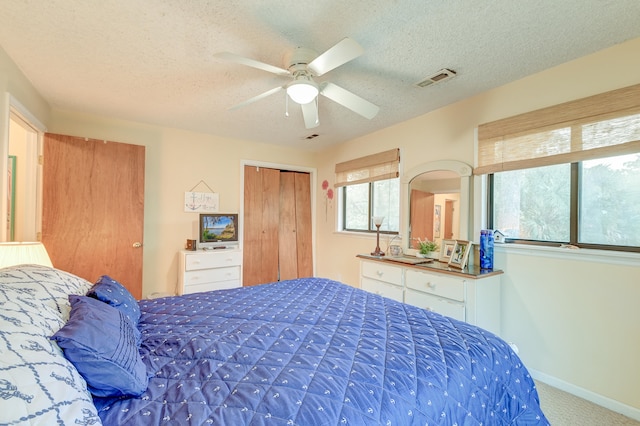 carpeted bedroom with ceiling fan, a textured ceiling, and a closet