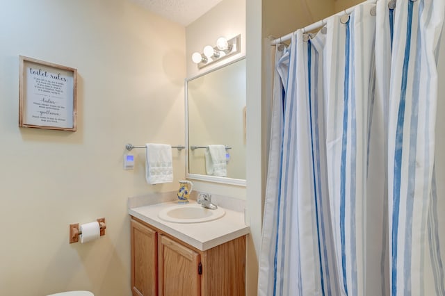 bathroom featuring toilet, vanity, a textured ceiling, and curtained shower