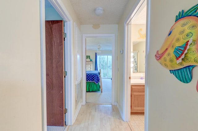 hallway featuring light wood-type flooring and a textured ceiling