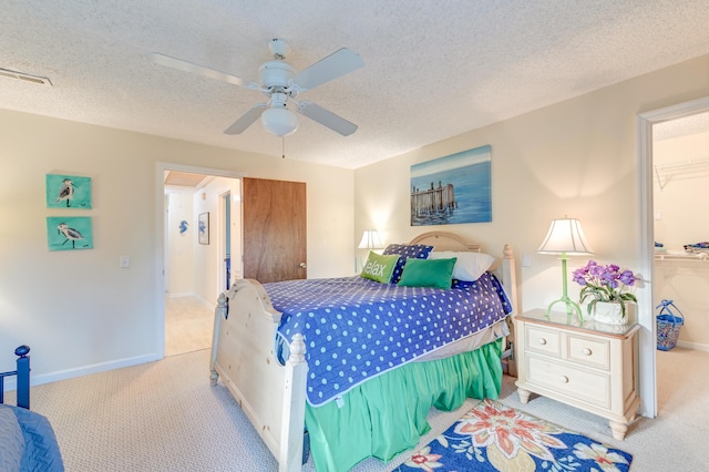 bedroom featuring a textured ceiling, light colored carpet, and ceiling fan