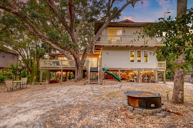 back house at dusk featuring a deck, an outdoor fire pit, and a jacuzzi